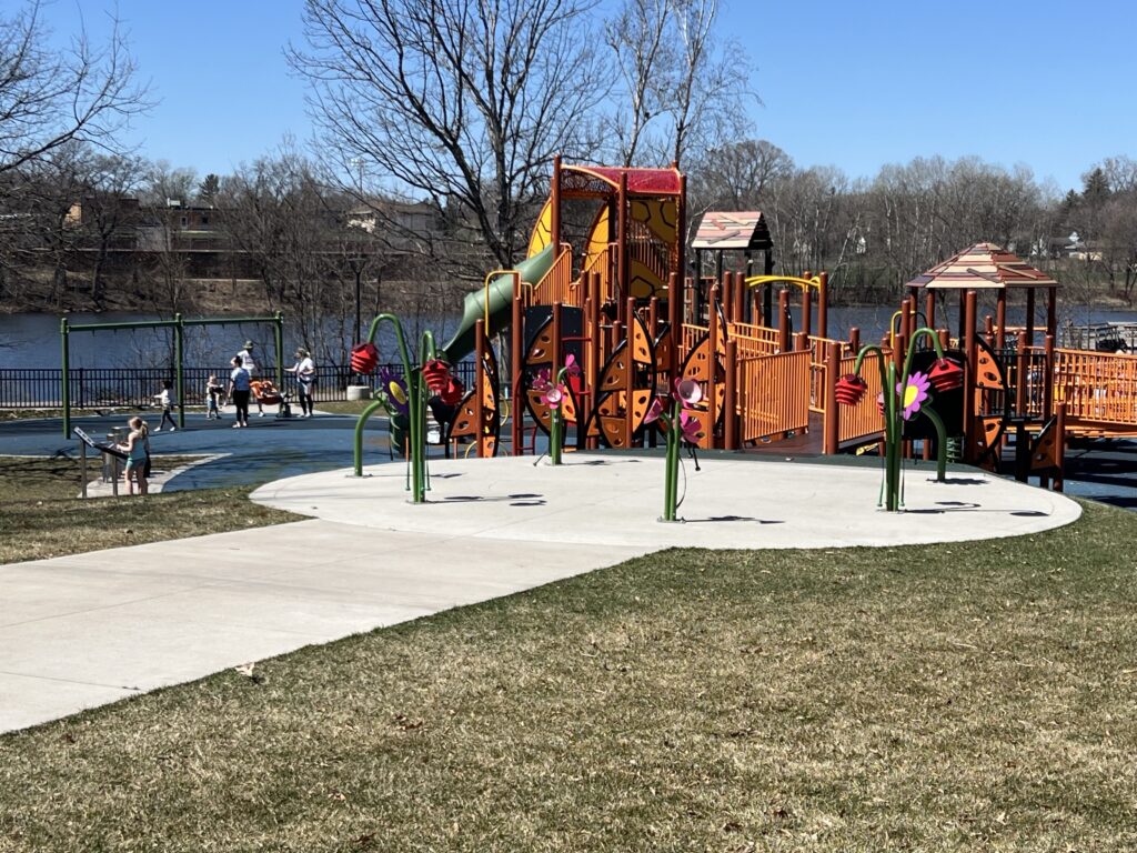 A picture of people using a playground with a lake in the background.